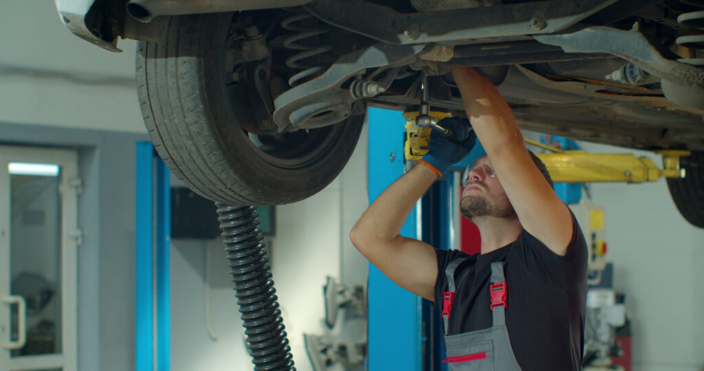 auto mechanic working underneath car